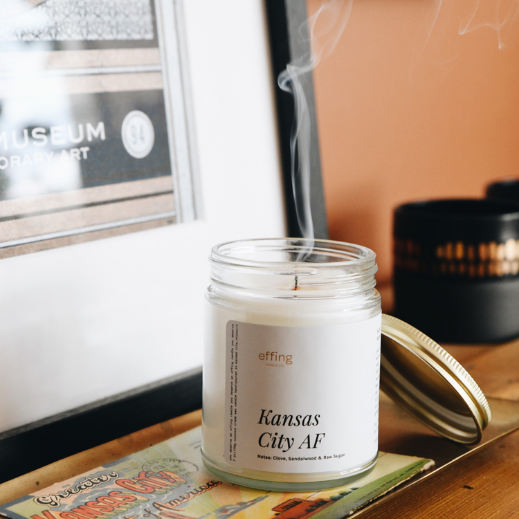 Kansas City AF wooden wick candle on a tray. It has just been blown out and a smoke curl is rising up the frame.