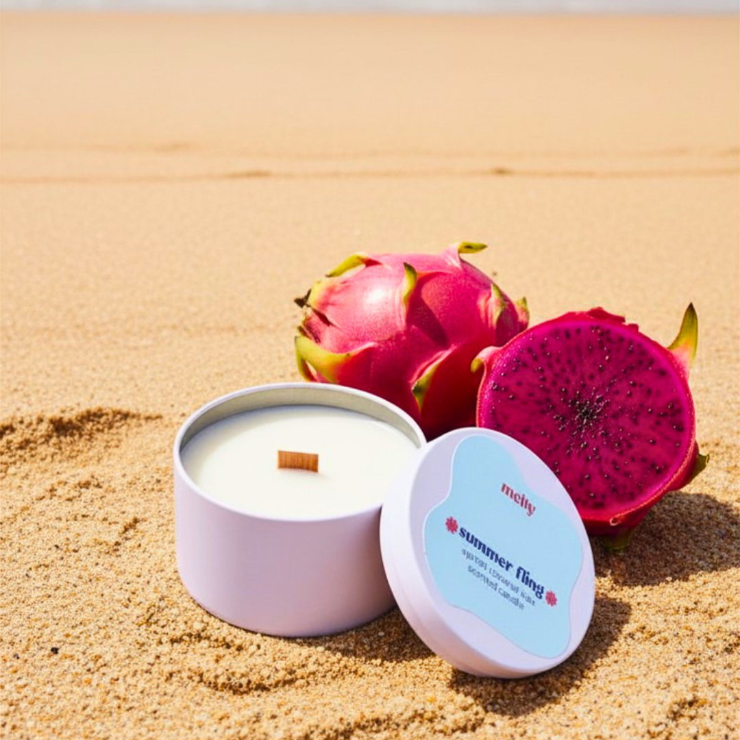 wooden wick candle on a beach with pink dragonfruit next to it 