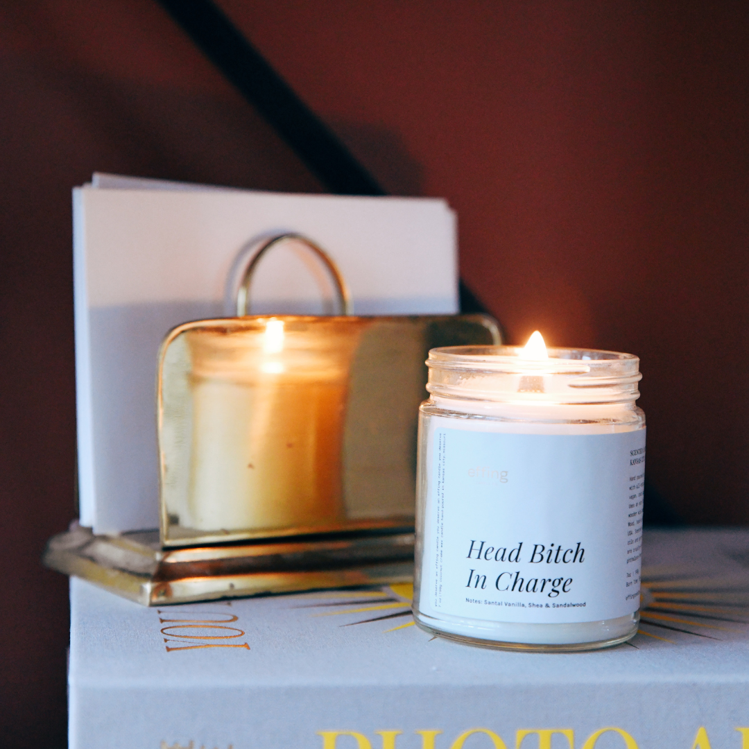 Head bitch in charge candle with a wooden wick that's lit 